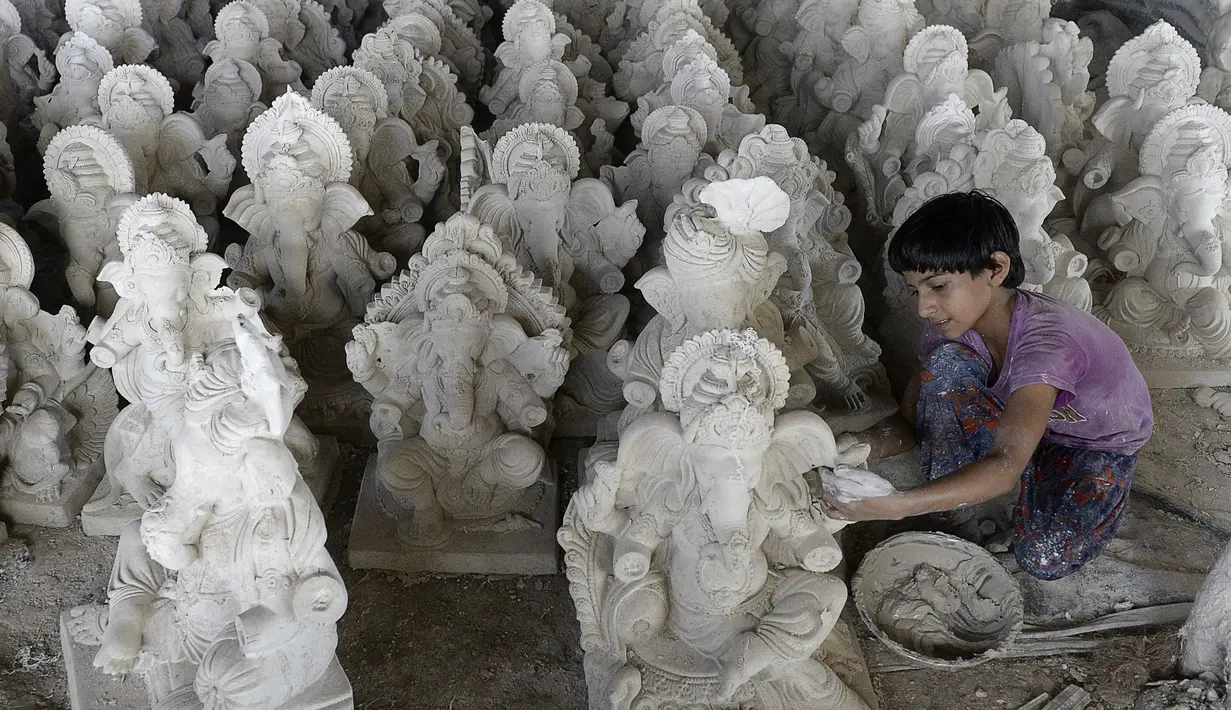 Perajin muda menyelesaikan pembuatan patung Dewa Ganesha di sebuah bengkel di pinggiran Hyderabad, India, Senin (29/6/2020). Patung Dewa Ganesha banyak ditemukan di berbagai penjuru India termasuk Nepal, Tibet, dan Asia Tenggara. (NOAH SEELAM/AFP)