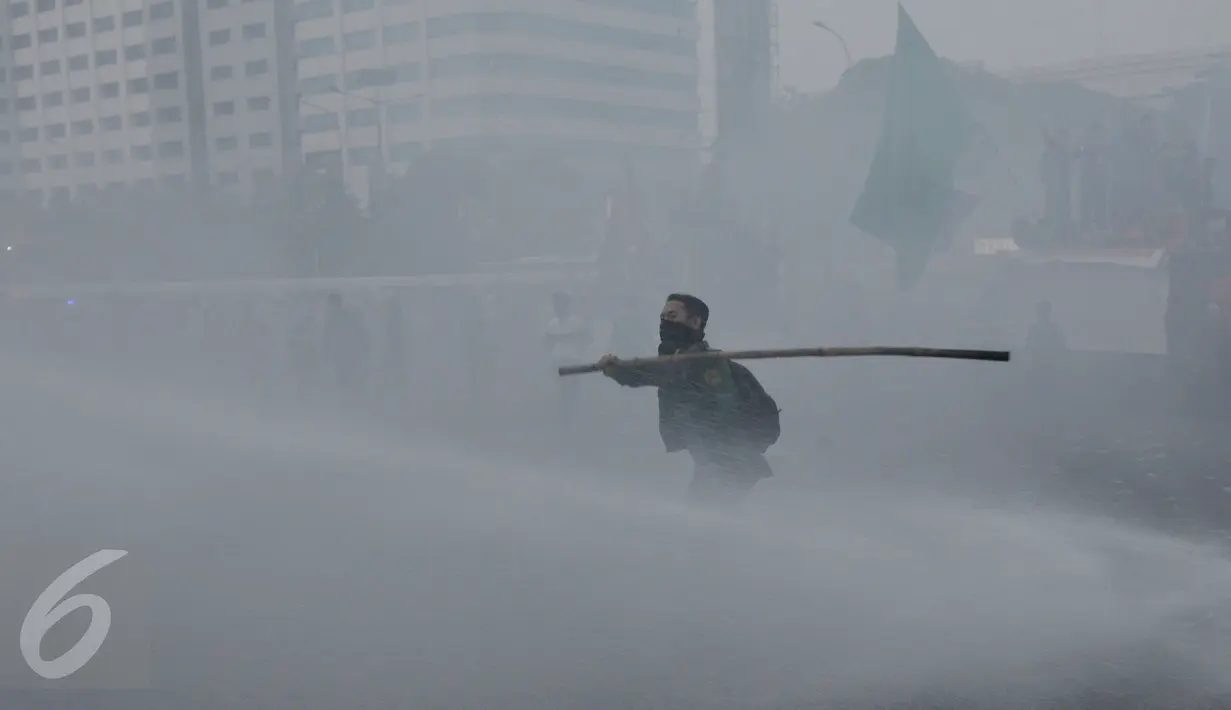 Seorang mahasiswa disemprot Water Canon saat aksi memperingati Hari Sumpah Pemuda di depan Gedung DPR, Senayan, Jakarta, Rabu (28/10/2015). Dalam aksinya para mahasiswa membakar ban. (Liputan6.com/Johan Tallo) 