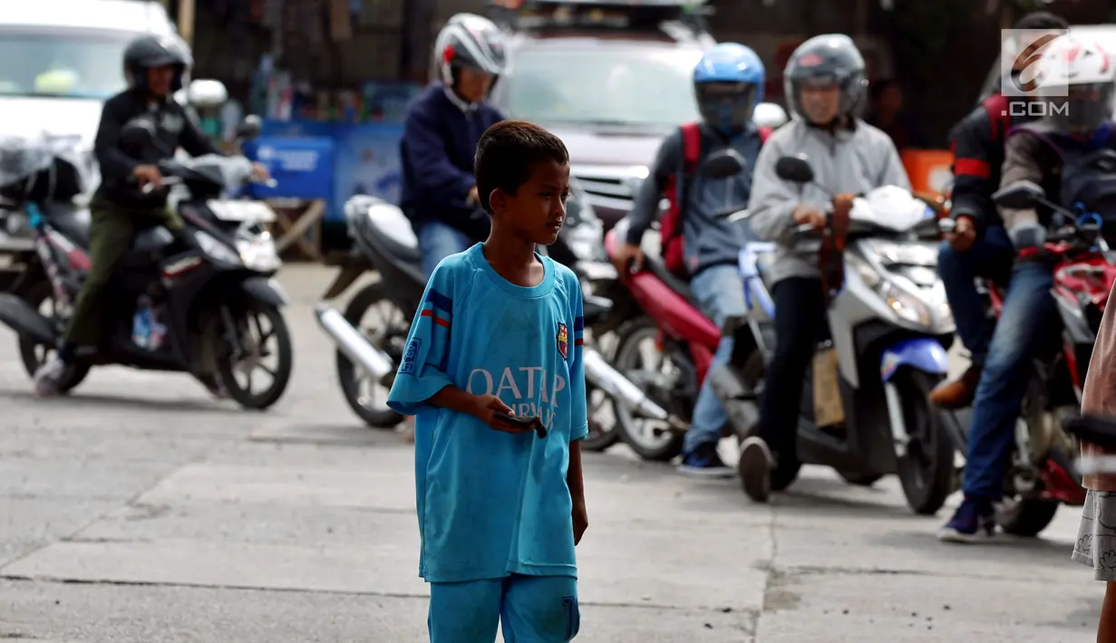 Seorang anak di SPBU Tanjung Pantura - Brebes mengais rejeki untuk membersihakan motor yang di kendarai pemudik dari Jakarta menuju kampung halamannya, Kamis (22/6). (Liputan6.com/Johan Tallo)