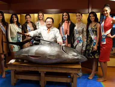 Sejumlah kontestan Miss Internasional berfoto bersama dengan Presiden Sushi-Zanmai, Kiyoshi Kimura (tengah) dan seekor tuna sirip biru seberat 250 Kg di Tokyo, Jepang (12/11). (AFP Photo/Toshifumi Kitamura)