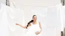 Gaya unik nan sederhana Nadine Chandrawinata lakoni maternity shoot. Nadine tampil mengenakan dress putih polos dengan latar kain-kain putih yang digantung bak cucian. [Foto: Instagram/nadinelist]
