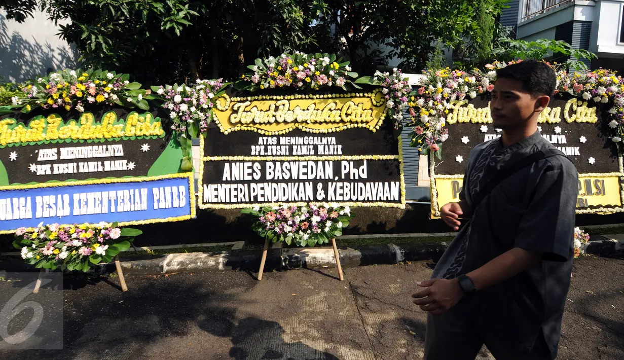 Warga melintasi karangan bunga duka cita wafatnya Ketua KPU Husni Kamil Manik di Kompleks KPU, Jakarta, Jumat (8/7). Sejumlah pejabat tinggi negara hadir melayat jenazah Husni Kamil Manik yang wafat, Kamis (7/7). (Liputan6.com/Helmi Fithriansyah)