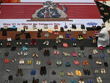 Seorang dokter mengambil foto instalasi seni dengan 321 pasang sepatu yang menandakan kematian akibat merokok dalam rangka memperingati Hari Tanpa Tembakau Sedunia di Pusat Paru Filipina, Quezon City, pinggiran kota Manila, Filipina, Selasa (31/5/2022). (JAM STA ROSA/AFP)