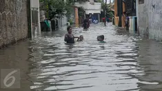 Warga menuntun anaknya melewati banjir yang mencapai pinggang orang dewasa di Rawa Buaya, Jakarta, Minggu (28/2/2016). Banjir terjadi akibat luapan Kali Mookervart yang diguyur hujan sejak malam. (Liputan6.com/Gempur M Surya)