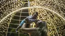 Seorang wanita mengangkat bayi di depan lampu jelang perayaan Natal di sepanjang pantai Copacabana, di Rio de Janeiro, Brasil (11/12/2021). Jelang perayaan Natal, taman dan pantai dihiasi lampu-lampu yang indah. (AP Photo/Bruna Prado)