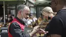 Seorang pramusaji memeriksa kartu kesehatan pengunjung di sebuah restoran di Paris, Senin (9/8/2021). Prancis mewajibkan semua orang menunjukkan kode QR yang membuktikan mereka memiliki Kartu Vaksinasi untuk memasuki restoran dan kafe atau bepergian di negara tersebut. (AP Photo/Adrienne Surprenant)