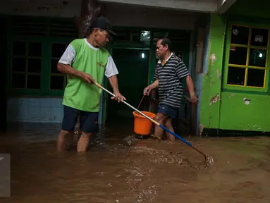 Warga membersihkan lumpur yang memenuhi rumahnya di Jalan Taman Harapan rt 02/03, Cawang, Kramat Jati, Jakarta, Senin (13/2). Warga mulai membersihkan lumpur setelah banjir yang menggenangi pemukiman mereka surut. (Liputan6.com/Gempur M Surya)