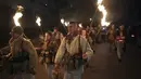 Penari membawa obor saat ritual kuno mengusir roh jahat di jalan-jalan Batanovci, Bulgaria, Kamis malam (13/1/2022). Setiap musim dingin di desa-desa seluruh negara Balkan, pria, wanita dan anak-anak mengenakan topeng ritual dan kostum melakukan tarian di sekitar api unggun. (AP/Valentina Petrova)