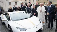 Paus Fransiskus saat menerima hadiah mobil Lamborghini Huracan di Vatikan, Rabu (15/11). Mobil Lamborghini ini oleh Paus rencananya akan dilelang dan hasilnya akan digunakan untuk membantu jemaah Kristen di Irak. (L'Osservatore Romano/Pool Photo via AP)