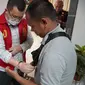 Petugas Kejati Sumsel memasangkan borgol di kedua lengan eks Presiden Sriwijaya FC, Hendri Zainuddin (Dok. Humas Kejati Sumsel / Nefri Inge)