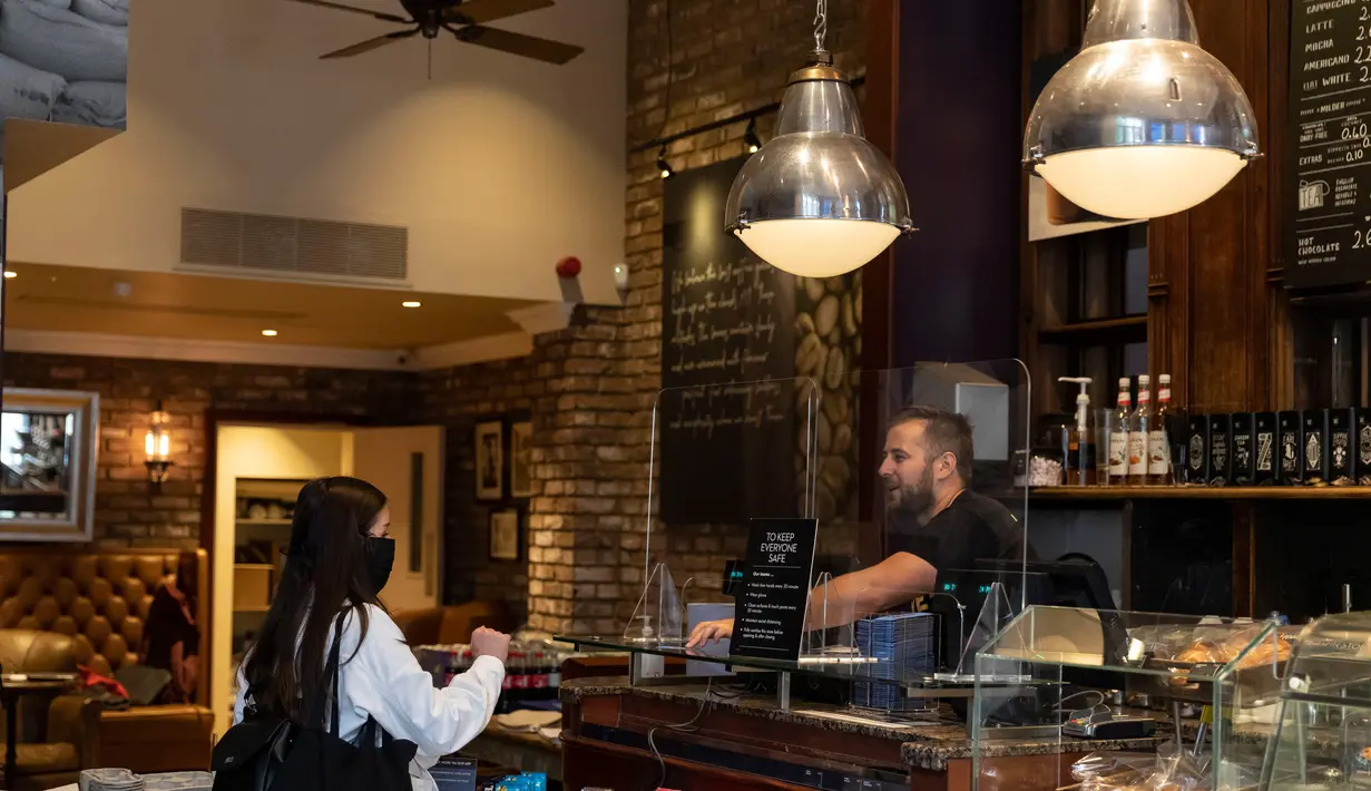 Seorang staf (kanan) berbicara dengan pelanggan di Caffe Nero yang dibuka kembali untuk layanan dibawa pulang di Maida Vale di London (10/6/2020). Beberapa kedai kopi di Inggris telah dibuka kembali untuk pengiriman atau layanan takeaway dengan mengikuti aturan jaga jarak sosial. (Xinhua/Han Yan)