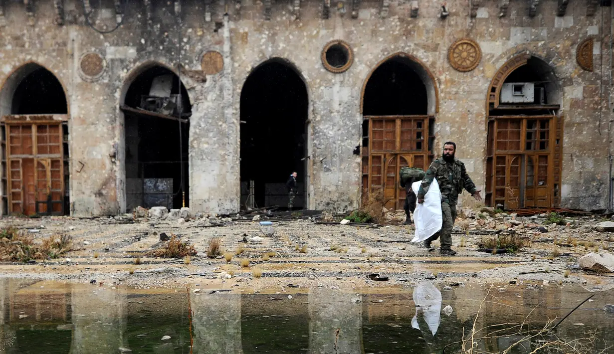 Anggota pasukan Presiden Suriah Bashar al-Assad berjalan di antara puing reruntuhan bangunan di kompleks Masjid Umayyad, Aleppo di Suriah, 13 Desember 2016. Konflik antara pemerintah dan pemberontak membuat masjid tersebut hancur. (REUTERS/Omar Sanadiki)