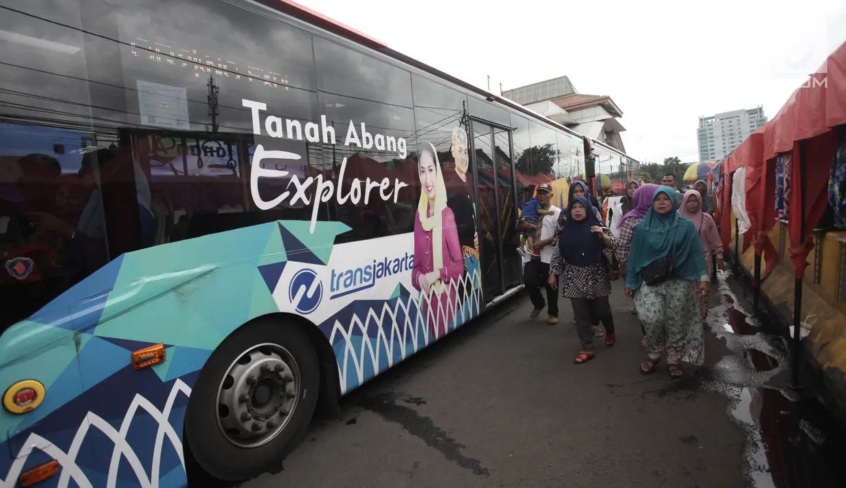 Sejumlah orang berjalan di samping bus Transjakarta Tanah Abang Explorer di Jalan Jatibaru, Tanah Abang, Jakarta, Sabtu (3/2). Bus Tanah Abang Explorer kembali beroperasi sampai 15.00 WIB selanjutnya dioperasikan oleh mikrolet (Liputan6.com/Arya Manggala)