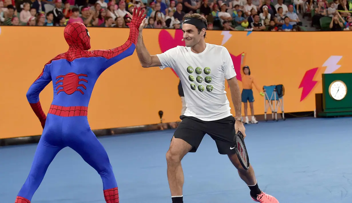 Petenis Swiss Roger Federer (kanan) bertepuk tangan dengan Spider-Man selama Hari Anak-anak menjelang turnamen tenis Australia Terbuka di Melbourne (13/1). (AFP Photo/Paul Crock)