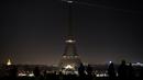 Sejumlah wisatawan mengamati pemadaman lampu di Menara Eiffel, Paris, Rabu (14/12). Lampu menara ikonik setinggi 300 meter itu dimatikan pada Rabu malam untuk menunjukkan dukungan bagi warga Aleppo di Suriah. (AFP PHOTO/PHILIPPE LOPEZ)