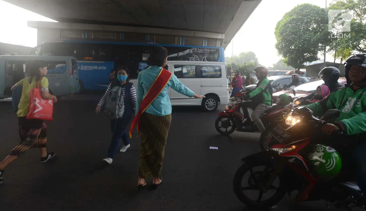Polwan Polres Jakarta Timur mengenakan kebaya ketika membantu pejalan kaki menyeberang lintas di Jalan Otista Raya, Jatinegara, Jumat (20/4). Para polwan itu berkebaya dalam mengatur lalu lintas untuk memperingati Hari Kartini. (Merdeka.com/Imam Buhori)