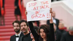 Aktris Manal Issa memegang poster bertuliskan "Hentikan Serangan di Gaza" saat menghadiri pemutaran film "Solo: A Star Wars Story" dalam Festival Film Cannes ke-71 di Cannes, Prancis (15/5). (AFP/Loic Venance)