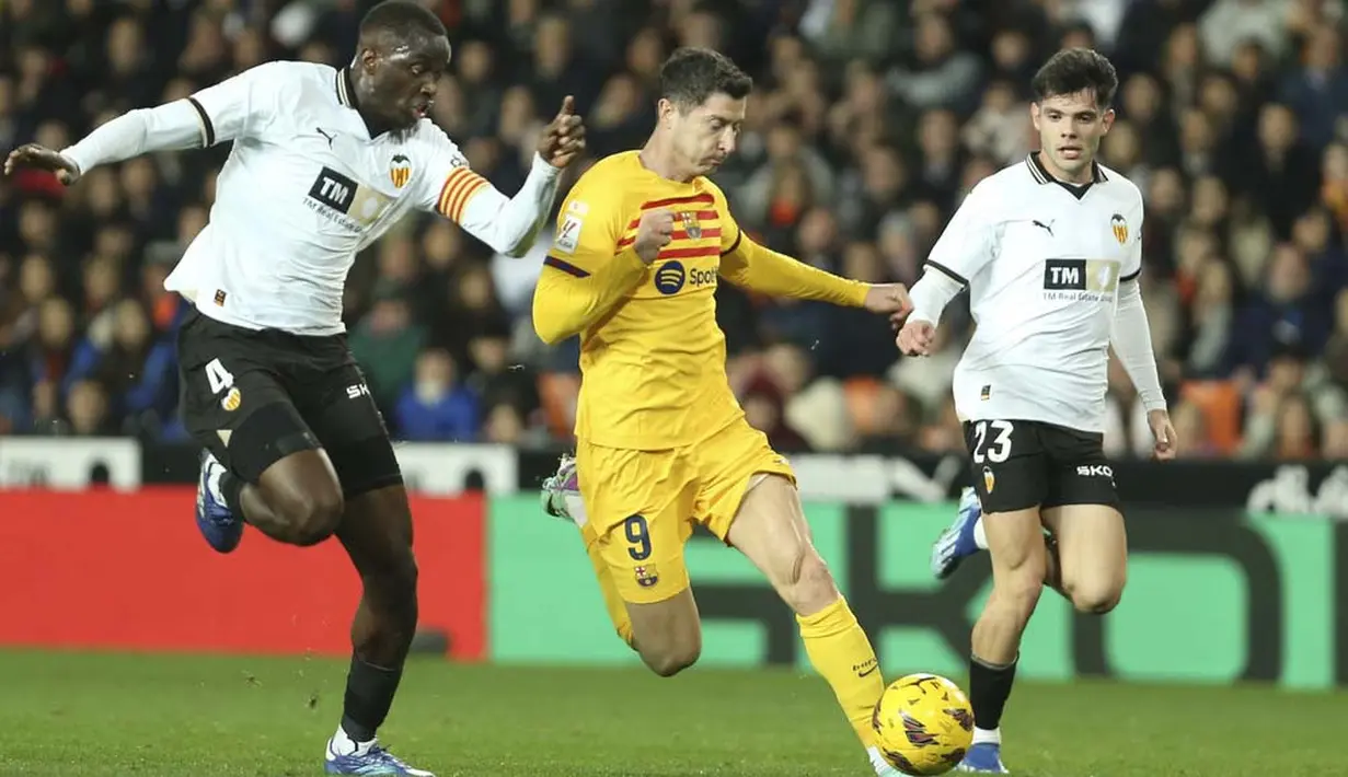 Pemain Barcelona, Robert Lewandowski, berusaha melewatkan pemain Valencia, Mouctar Diakhaby, pada laga pekan ke-17 La Liga 2023/2024 di Stadion Mestalla, Minggu (17/12/2023). Bomber asal Polandia itu berusaha keras mencetak gol dan membawa timnya menang. (AP Photo/Alberto Saiz)