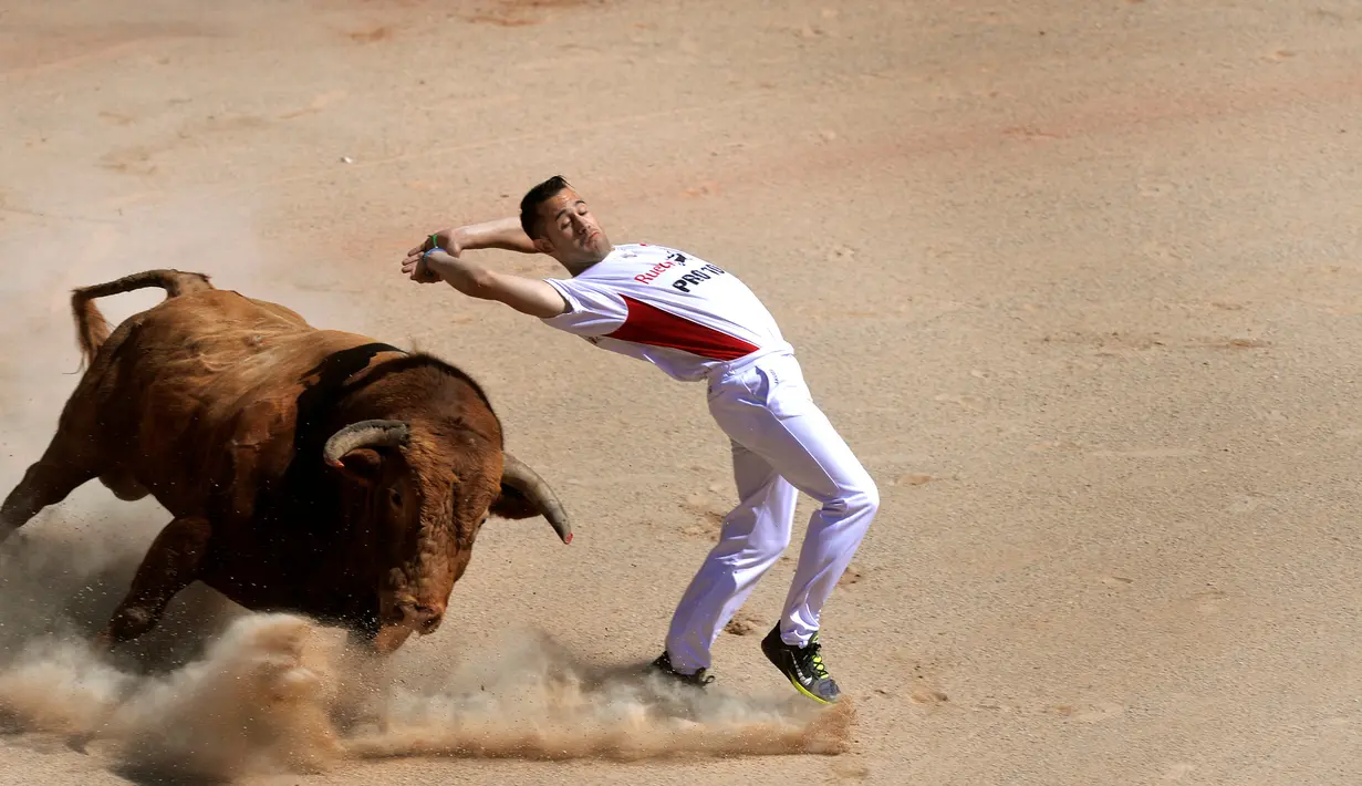 Seorang recortador mengelaka serudukan banteng selama Festival San Fermin di Pamplona, Spanyol, Sabtu (9/7).Para recortador melakukan aksi berbahaya tanpa menggunakan alat keamanan apapun. (REUTERS / Vincent West)