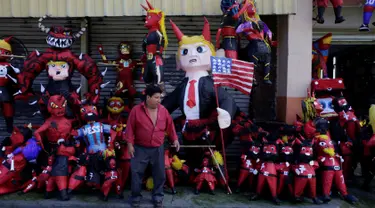 Seorang penjual pinata berdiri di depan dagangannya sebelum perayaan tradisional, Pembakaran Iblis di Guatemala City, Guatemala (7/12). Pinata adalah permainan yang biasanya ditujukan untuk anak-anak kecil saat merayakan pesta. (Reuters/Luis Echeverria)