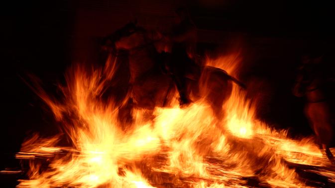 Seorang pria menunggangi kuda melewati api unggun saat festival Luminarias di San Bartolome de Pinares, Spanyol, Jumat (16/1/2020). Biasanya tradisi berkuda menembus api dilakukan pada satu hari sebelum perayaan Santo Antonius, yakni pada malam hari hingga tengah malam. (AP Photo/Manu Fernandez)