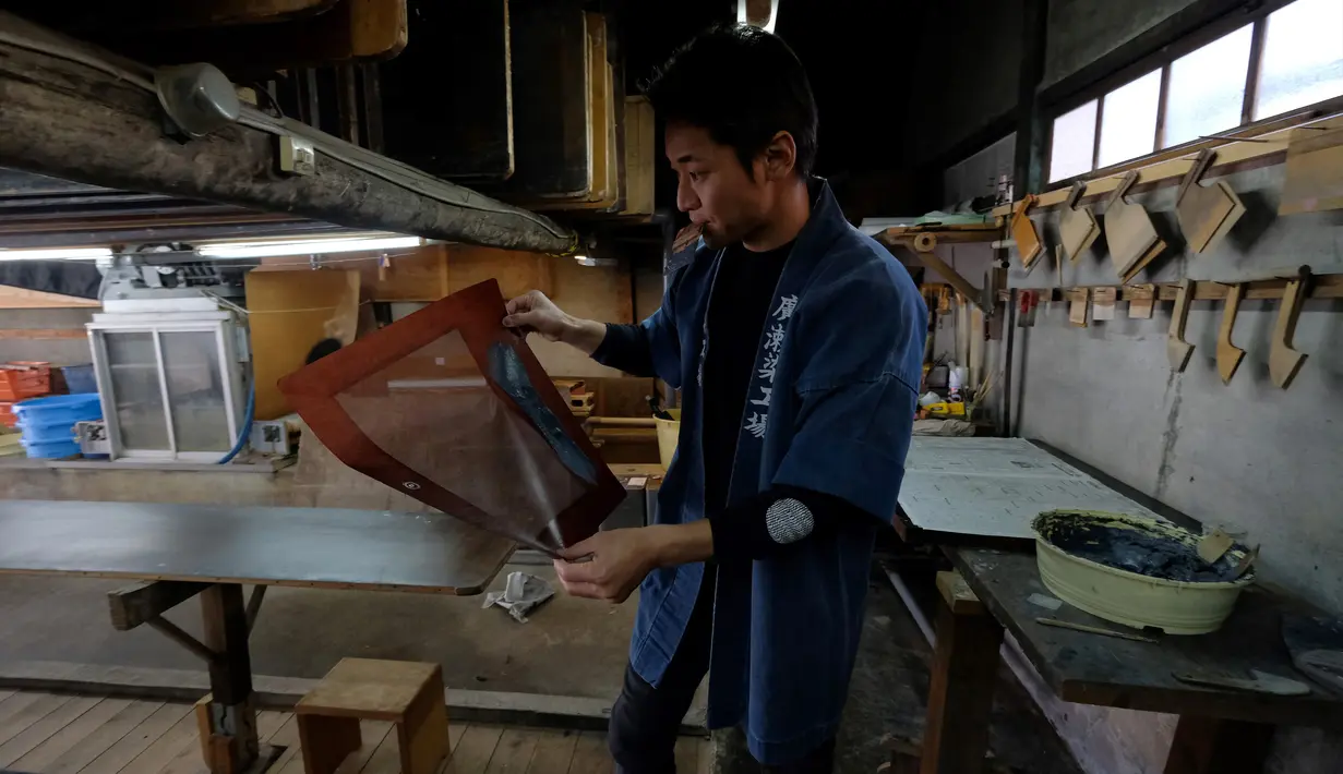 Seorang pengrajin bernama Yuichi Hirose menunjukkan cetakan stensil yang digunakan untuk mewarnai kain putih menjadi kimono di Tokyo, Jepang (1/3). Kimono adalah pakaian tradisional Jepang yang berasal dari era Muromachi (1392-1568). (AFP/Kazuhiro Nogi)