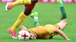 Pemain Australia, Mathew Leckie terjatuh saat berduel dengan pemain Kamerun pada laga grup B Piala Konfederasi 2017 di Saint Petersburg Stadium, (22/6/2017). (AFP/Mladen Antonov)