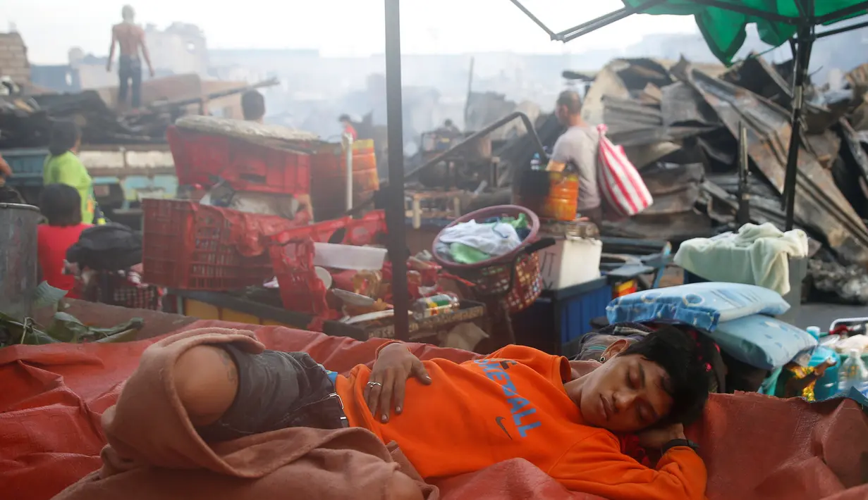 Seorang warga beristirahat ditengah reruntuhan bangunan yang hangus terbakar usai si jago merah melahap rumahnya di  Quezon, Metro Manila di Filipina (28/12). (REUTERS/Erik De Castro)