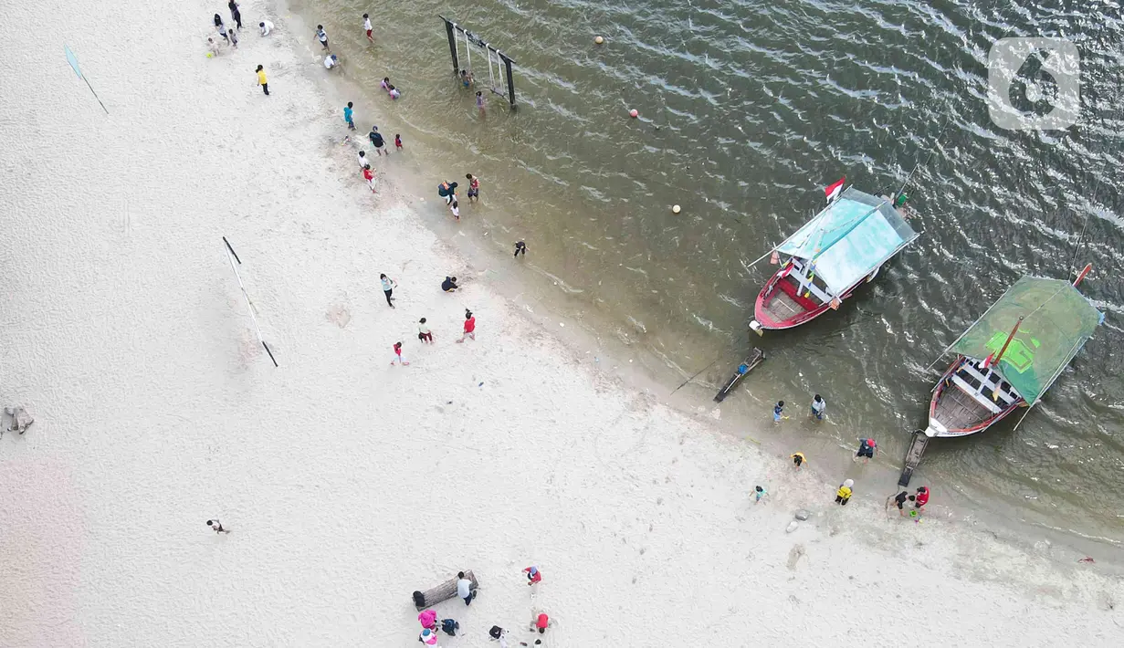Pemandangan udara warga berlibur di Pantai Ancol, Pademangan, Jakarta Utara, Rabu (1/6/2022). Libur Nasional Hari Lahir Pancasila, dimanfaatkan warga mengajak sanak saudara tamasya di Pantai Ancol. (Liputan6.com/Herman Zakharia)
