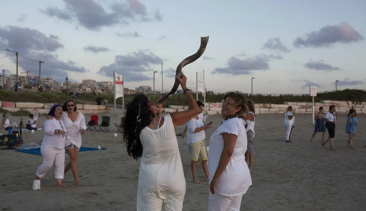 Seorang wanita memegang shofar sebelum upacara Tashlich, di pantai di Tel Aviv, Israel, (14/9/2021). Tashlich, yang berarti 'membuang' dalam bahasa Ibrani, adalah praktik dimana orang-orang Yahudi pergi ke genangan air besar dan secara simbolis 'membuang' dosa-dosa mereka. (AP Photo/Maya Alleruzzo)