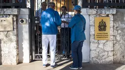 Pengunjung menunggu di depan pintu masuk kedutaan besar Kanada yang berada di Hanava, Kuba, Selasa (17/3).  Kanada memulangkan staf diplomat beserta keluarga mereka dari Kuba karena terserang penyakit misterius. (AP/Desmond Boylan)