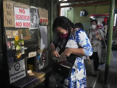 Seorang wanita memegang kartu vaksinasinya sebelum menaiki jip penumpang di sebuah terminal di kota Quezon, Senin (17/1/2022). Pemerintah Filipina melarang orang yang belum menerima vaksin COVID-19 untuk naik transportasi umum di ibu kota Manila mulai Senin ini. (AP Photo/Aaron Favila)