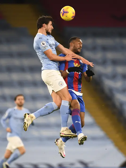 Bek Manchester City, Ruben Dias berebut bola dengan pemain Crystal Palace, Jordan Ayew  pada pertandingan lanjutan Liga Inggris di Stadion Etihad, Senin (18/1/2021).  Crystal Palace menempati posisi ke-13 setelah mengoleksi 23 poin. (Peter Powell/Pool via AP)