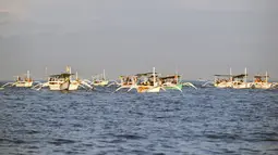 Wisatawan di atas perahu selama tamasya menyaksikan lumba-lumba di perairan Pantai Lovina di Singaraja, Bali, Jumat (30/10/2020). Pantai Lovina merupakan salah satu destinasi pariwisata di Bali yang sering dikunjungi untuk menikmati matahari terbit dan lumba-lumba di laut lepas (SONNY TUMBELAKA/AFP)