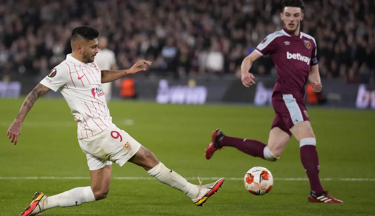 Penyerang Sevilla Jesus Corona menembak ke gawang yang disaksikan gelandang West Ham Declan Rice pada leg kedua Liga Europa 2021/2022 di Stadion London, Jumat (18/3/2022) dini hari WIB. West Ham United menang dramatis atas Sevilla dengan skor 2-0. (AP Photo/Matt Dunham)