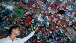 Seorang pria melihat instalasi seni gantung sekelompok seniman yang terbuat dari sisa-sisa plastik, kaleng dan wadah di sebuah pameran "Reduce the Litter" di Pusat Kebudayaan Prancis di Hanoi (15/7/2019). Pameran ini mengambil perspektif tentang produksi dan konsumsi. (AFP Photo/Nhac Nguyen)