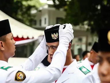 Anggota Paskibraka 2016 merapikan peci rekannya saat bersiap melaksanakan gladi bersih Upacara HUT ke-71 Kemerdekaan RI di Istana Merdeka, Jakarta, Senin (15/8). (Liputan6.com/Faizal Fanani)