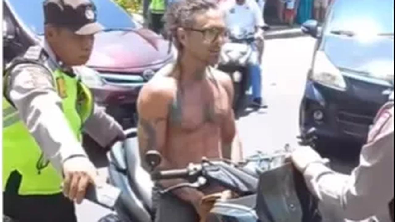 Sebuah video yang diunggah akun Instagram @lowslow.indonesia merekam saat seorang turis asing yang mengendarai motor dengan tak menggunakan helm dan telanjang dada mengamuk saat diberhentikan polisi.