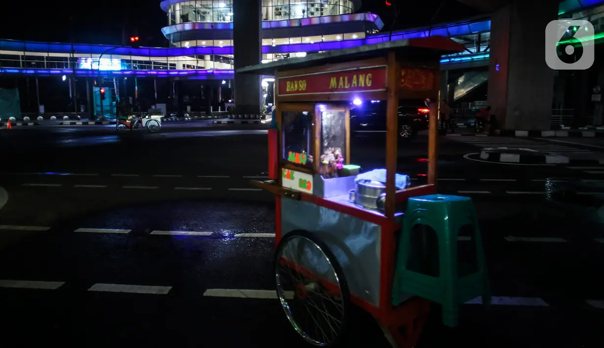Pedagang melintas dekat halte CSW yang berhiaskan lampu warna-warni di Kawasan Kebayoran Baru, Jakarta, Kamis (5/8/2021). Proyek pembangunan skybridge untuk integrasi Halte Transjakarta CSW dengan Stasiun MRT ASEAN itu mengusung konsep desain Cakra Selaras Wahana. (Liputan6.com/Johan Tallo)