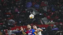 Gelandang Barcelona, Sergio Busquets berebut bola udara dengan pemain Sevilla, Thomas Delaney pada pertandingan La Liga Spanyol di stadion Ramon Sanchez-Pizjuan, Spanyol, Rabu (22/12/2021). Hasil ini tidak mengubah posisi Barcelona pada peringkat ketujuh dengan 28 poin. (AP Photo/Angel Fernandez)