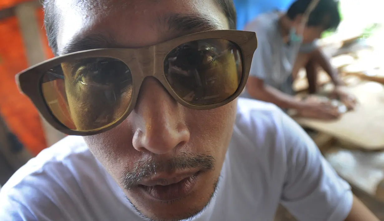 Perajin mencoba kacamata berbahan kayu buatannya di Gang  Madrasah, Pamulang, Tangerang Selatan, Senin (21/1). Dalam sehari, pengrajin mampu menyelesaikan dua buah kacamata yang dijual Rp 200 ribu hingga Rp 500 ribu per buah. (Merdeka.com/Arie Basuki)