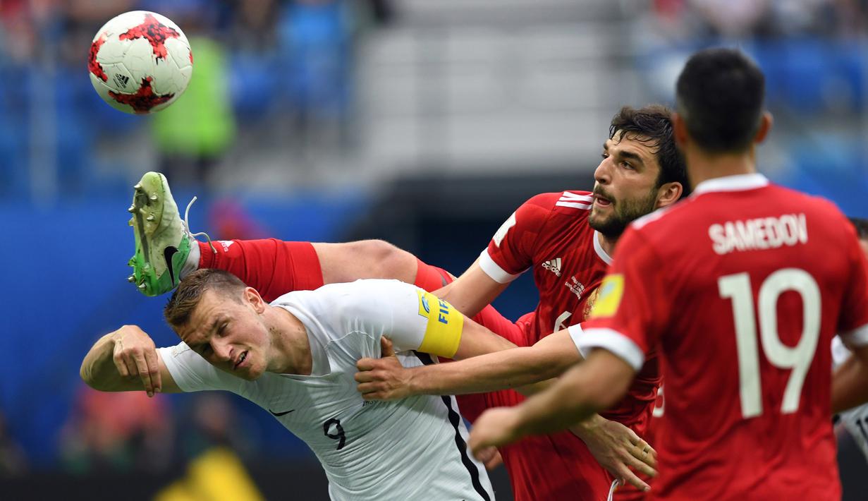 Aksi bek Rusia, Georgiy Dzhikiya (tengah) menghalau bola dari sundulan pemain Selandia Baru, Chris Wood pada laga perdana Piala Konfederasi 2017 grup A di Krestovsky Stadium, Saint-Petersburg, (17/6/2017).  (AFP/Kirill Kudryavtsev)