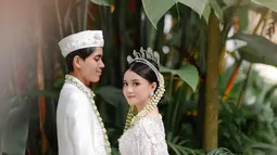 Dalam gambar yang diunggah, Kayess dan Celiboy terlihat mengenakan busana adat Jawa sebagai pengantin. Mereka dengan bangga menunjukkan foto buku pernikahan mereka. (Liputan6.com/IG/@ewkharis)