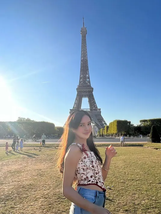 Menikmati pemandangan di Menara Eiffel pada sore hari, Beby Tsabina tampil feminin dengan atasan bertali bermotif bunga dan potongan segitita terbalik di bagian wajah. Sehingga menampilkan sedikit tubuhnya yang ramping. (instagram/bebytsabina)