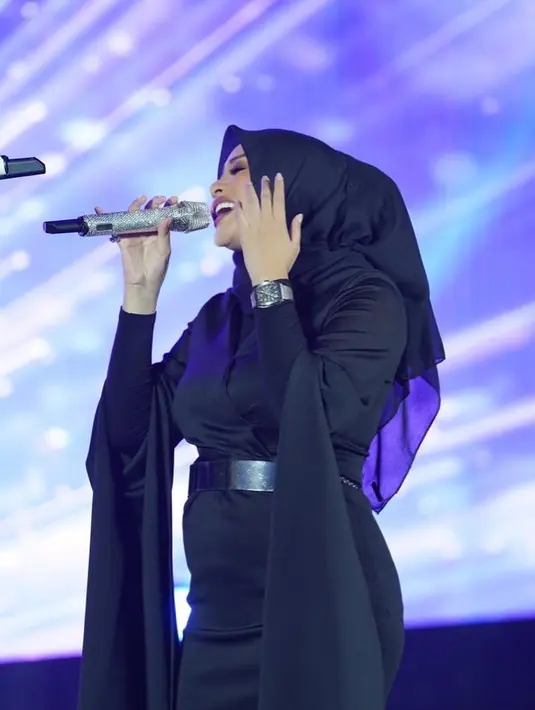 Dress hitam yang sleek dan simple dengan aksen pada tangan yang menjuntai serta belt untuk memberi siluet dan mengekspos baby bump (Foto: Instagram @aurelie.hermansyah)