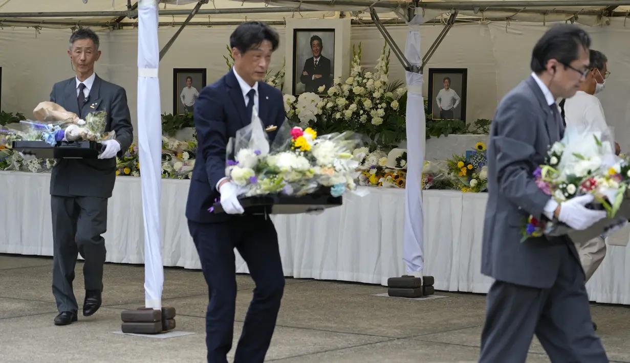 Bunga yang dipersembahkan oleh para pelayat dipindahkan dari altar saat semakin banyak orang datang dan berdoa untuk mantan Perdana Menteri Jepang Shinzo Abe di kuil Zojoji, Tokyo, Sabtu (8/7/2023). (AP Photo/Shuji Kajiyama)