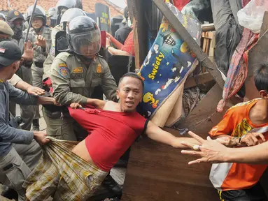 Aparat keamanan melakukan aksi membawa paksa warga yang mencoba bertahan saat penggusuran Pasar Ikan, Penjaringan, Jakarta, Senin (11/4). Bentrokan terjadi antara petugas dan warga yang menolak penggusuran di kawasan tersebut (Liputan6.com/Gempur M Surya)