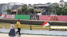 Warga berjalan di depan mural bertema Kemerdekaan RI pada dinding turap Sungai Ciliwung di kawasan Kampung Melayu, Jakarta, Minggu (16/8/2020). Mural karya petugas Pekerja Penanganan Sarana dan Prasarana Umum (PPSU) itu dibuat dalam rangka memeriahkan HUT ke-75 RI. (Liputan6.com/Immanuel Antonius)