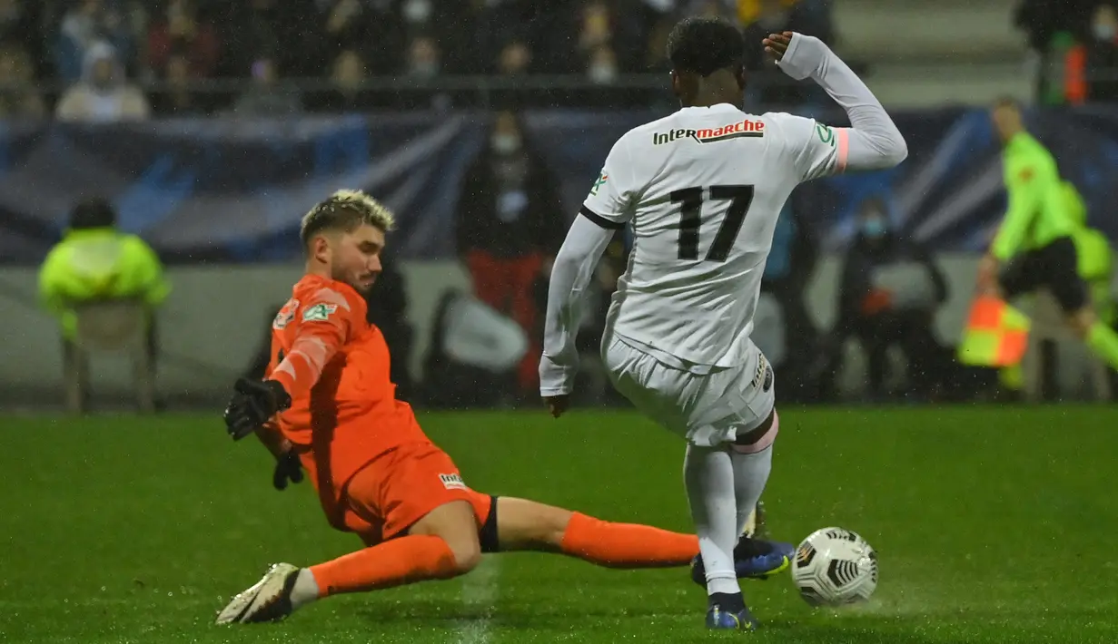 Gelandang Paris Saint-Germain (PSG) Eric-Junior Dina-Ebimbe (kanan) memainkan bola di sebelah kiper klub divisi empat, Vannes OC, Clement Petrel dalam babak 32 besar Piala Prancis di Stade de la Rabine, Selasa (4/1/2021) dini hari WIB. PSG menang 4-0 lewat hattrick Kylian Mbappe. (LOIC VENANCE/AFP)