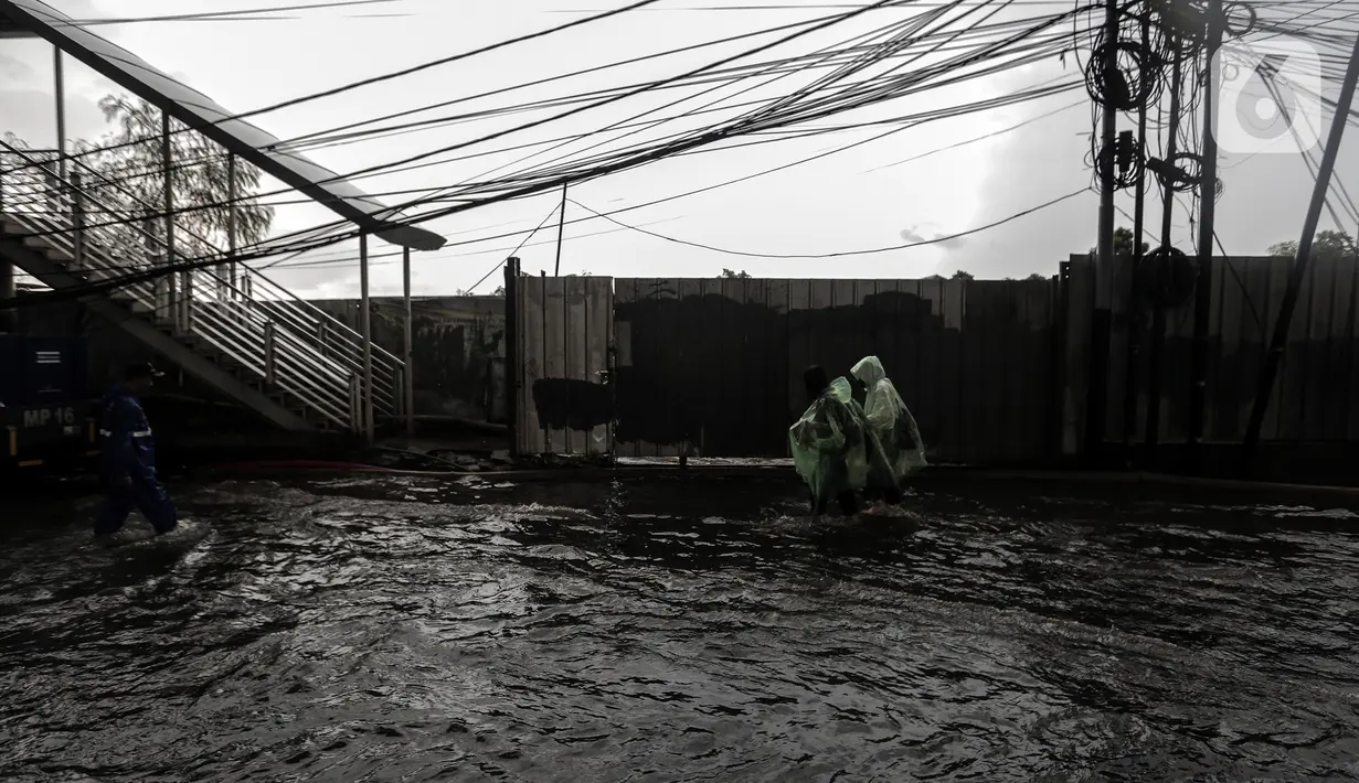 Warga berjalan melintasi banjir yang menggenangi kawasan Seskoal - Cipulir, Jakarta, Selasa (4/4/2022). Hujan yang mengguyur wilayah Ibu Kota Jakarta mengakibatkan banjir menggenangi kawasan Simpang Seskoal, Kebayoran Lama, Jakarta. Banjir setinggi 50cm - 1 meter disebabkan saluran pembuangan berukuran kecil tersumbat. (Liputan6.com/Johan Tallo)